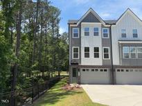 Charming townhome with gray and white siding, large windows, and an attached two-car garage on a sunny day at 2126 Opulent Oaks Ln # 14, Durham, NC 27713