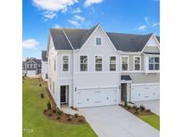 New construction townhome with white siding, black roof, two car garage, and a manicured lawn at 28 Nettle Ln # 235, Clayton, NC 27520