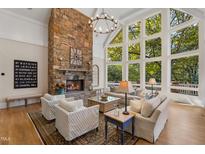 Bright living room boasts stone fireplace, hardwood floors, and large windows with natural light and views at 32430 Archdale, Chapel Hill, NC 27517