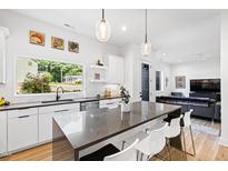 Bright kitchen features a spacious island with seating, stainless steel appliances, and view of the front yard at 1511 Malta Ave, Raleigh, NC 27610