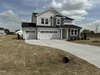 Inviting two-story home featuring a spacious three-car garage and neutral-colored exterior at 57 Bering Cir, Angier, NC 27501