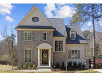 Charming brick home featuring classic shutters, a gable roof, and an inviting front entrance with elegant columns at 126 E Drewry Ln, Raleigh, NC 27609