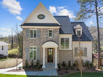 Charming two-story brick home featuring gray shutters, a covered entry, and manicured landscaping at 126 E Drewry Ln, Raleigh, NC 27609