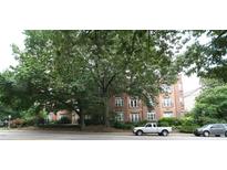 Brick apartment building featuring large shade trees, street view, and visible tenant parking at 1001 Hillsborough St # 304, Raleigh, NC 27603