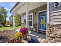 Inviting front porch with colorful mums and decorative accents at 1104 Braemar Highland Dr, Zebulon, NC 27597