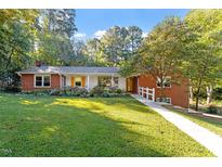 Charming red brick home features lush front lawn, walkway, and mature trees at 3615 Octavia St, Raleigh, NC 27606