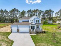 Charming two-story home featuring a three-car garage, front porch, and a beautifully landscaped yard at 236 Alden Way, Angier, NC 27501