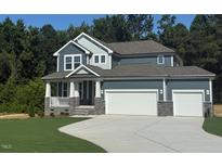 Inviting home featuring a two-car garage, covered porch, stone accents, and well-manicured lawn at 236 Alden Way, Angier, NC 27501