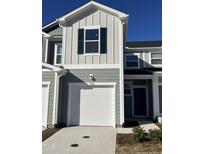 Charming exterior of a two-story home featuring a white garage door, light green siding and black shutters at 1050 Mountain Crown St, Durham, NC 27703