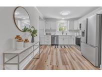 Bright kitchen with white cabinets, stainless steel appliances, and wood-look floors at 3440 Apache Dr, Raleigh, NC 27609