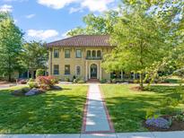 Stunning two-story brick home with a red tile roof, manicured lawn, and colorful landscaping at 1015 Minerva Ave, Durham, NC 27701