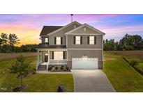 Charming two-story home with a front porch, attached garage, and well-maintained landscaping at 15 Diamond Creek Dr, Zebulon, NC 27597