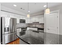 Modern kitchen featuring stainless steel appliances, a tile backsplash, and granite countertops with pendant lighting at 222 Glenwood Ave # 508, Raleigh, NC 27603