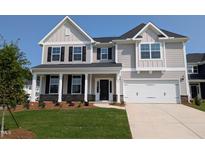 Charming two-story home featuring a manicured lawn, a two-car garage, and a welcoming front porch with stone accents at 120 Berry Mill Ln # 129, Raleigh, NC 27603