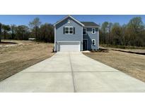Charming two-story home with a garage and a long driveway on a sunny day at 259 Johnson Ridge Way, Four Oaks, NC 27524
