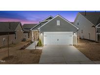 Charming home featuring a gray exterior, complemented by a two-car white garage, and a well-maintained lawn at 1829 Hydrangea Way, Fuquay Varina, NC 27526