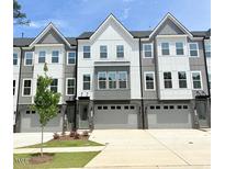 Modern townhome exterior features a two-car garage and a well-maintained lawn at 2007 Opulent Oaks Ln # 24, Durham, NC 27713