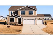 Two-story home featuring a three-car garage, stone accents, and manicured landscaping at 224 Bering Cir, Angier, NC 27501