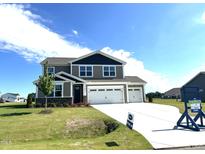Two-story home featuring a three-car garage, well-manicured lawn, and a charming dark grey and beige exterior at 224 Bering Cir, Angier, NC 27501