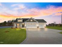 Charming home featuring a three-car garage, stone accents, well manicured lawn, and a large driveway at 32 Boyce Ct, Sanford, NC 27332
