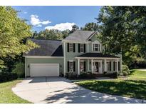 Two-story light green house with a white door, black shutters, and a two-car garage at 11308 Timbergrove Ln, Raleigh, NC 27614