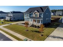 Beautiful two-story home featuring blue siding, stone accents, a covered porch, and well-maintained landscaping at 102 Dungannon Loop, Clayton, NC 27520