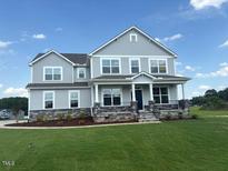 Two-story home boasting large windows, gray siding, and a well-manicured lawn under a blue sky at 111 Demascus Way # 021, Four Oaks, NC 27524