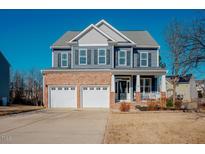 Two-story home with brick and siding exterior, two-car garage, and front porch at 454 Big Willow Way, Rolesville, NC 27571
