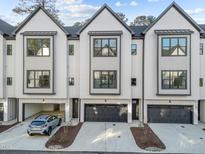 Modern townhome featuring a stylish white exterior with black accents, garages, and manicured landscaping at 811 Maple Berry Ln # 103, Raleigh, NC 27607