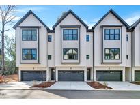 Modern townhomes boast a crisp white exterior, dark trim, and attached garages for convenient parking at 811 Maple Berry Ln # 105, Raleigh, NC 27607