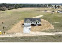 Expansive aerial view of a charming white home surrounded by a sprawling green landscape at 233 Surles Rd, Benson, NC 27504