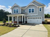 Charming two-story home with a covered porch, two-car garage, and manicured front yard at 33 Macy Cir, Wendell, NC 27591