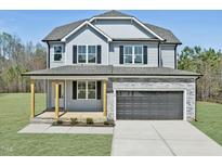 Beautiful two-story home featuring a gray exterior, stone accents, a welcoming porch, and an attached two-car garage at 40 Sunrise Ct, Spring Hope, NC 27882