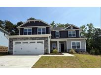 Charming two-story home featuring a stone-accented facade, a two-car garage, and a neatly maintained lawn at 73 High Hampton Way, Fuquay Varina, NC 27526