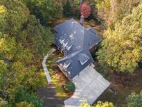 Stunning aerial view of a home with mature trees and a well-manicured lawn, featuring a classic roof and spacious driveway at 5504 Spring Bluffs Ln, Raleigh, NC 27606