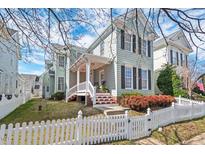 Charming two-story home with a welcoming front porch and a manicured lawn, complemented by a classic white picket fence at 102 Carpenter Town Ln, Cary, NC 27519