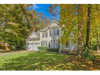 Two-story home with a two-car garage, lush green lawn, and mature trees, set under a sunny blue sky at 413 Chadwick Ln, Efland, NC 27243