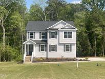 Charming two-story home with gray siding, a covered entryway, manicured landscaping, and a lush green lawn at 266 Fast Pitch Ln, Four Oaks, NC 27524