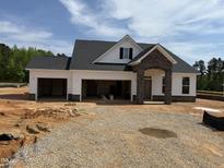 New construction home featuring a three-car garage, stone accents, and a covered entryway at 52 Macy Cir, Wendell, NC 27591