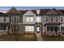 Charming townhome featuring stone accents, a welcoming entrance, and manicured landscaping at 951 Alma Railway Dr # 561, Wake Forest, NC 27587