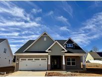 A charming new home with a brick facade, gray siding, and a well-manicured lawn under a partly cloudy sky at 1044 Fairhaven Dr # 100, Mebane, NC 27302