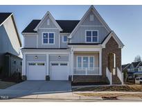 Two-story home featuring a two car garage, brick accents, and a covered front porch at 100 Mossy Falls Way, Wendell, NC 27591