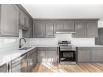 This kitchen features stainless steel appliances, gray cabinets, light countertops, and hardwood floors at 234 Crumpler Rd, Kenly, NC 27542