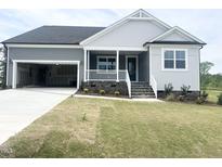Charming single-Gathering home boasts a welcoming front porch, well-manicured lawn, and attached two-car garage at 490 Barbour Farm Ln, Four Oaks, NC 27524