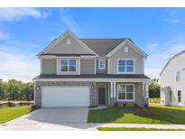 Charming two-story home featuring a stone-accented front, attached garage, and well-manicured lawn at 1224 Cricket St, Elon, NC 27244