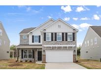 Charming two-story home featuring a stone facade, black shutters, and a two-car garage at 1228 Cricket St, Elon, NC 27244