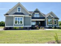 Beautiful home featuring gray siding, white trim, large windows, and a manicured green lawn at 70 Water Willow Ln, Zebulon, NC 27597