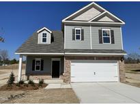 Charming two-story home featuring a two-car garage, brick accents, gray siding, and a neatly landscaped front yard at 162 Deodora Ln, Cameron, NC 28326
