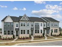 New townhomes with modern facades, landscaping, and inviting sidewalks under a partly cloudy sky at 810 Barlow Dr, Knightdale, NC 27545