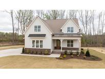 Charming two-story home with a welcoming front porch and meticulously landscaped front yard at 8624 Dukes Lake Rd, Zebulon, NC 27597